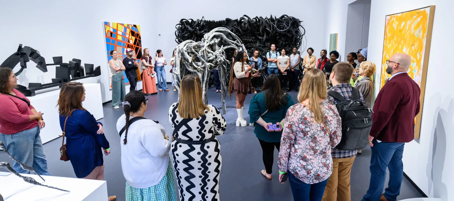 A poet performs in a gallery with many people surrounding her.