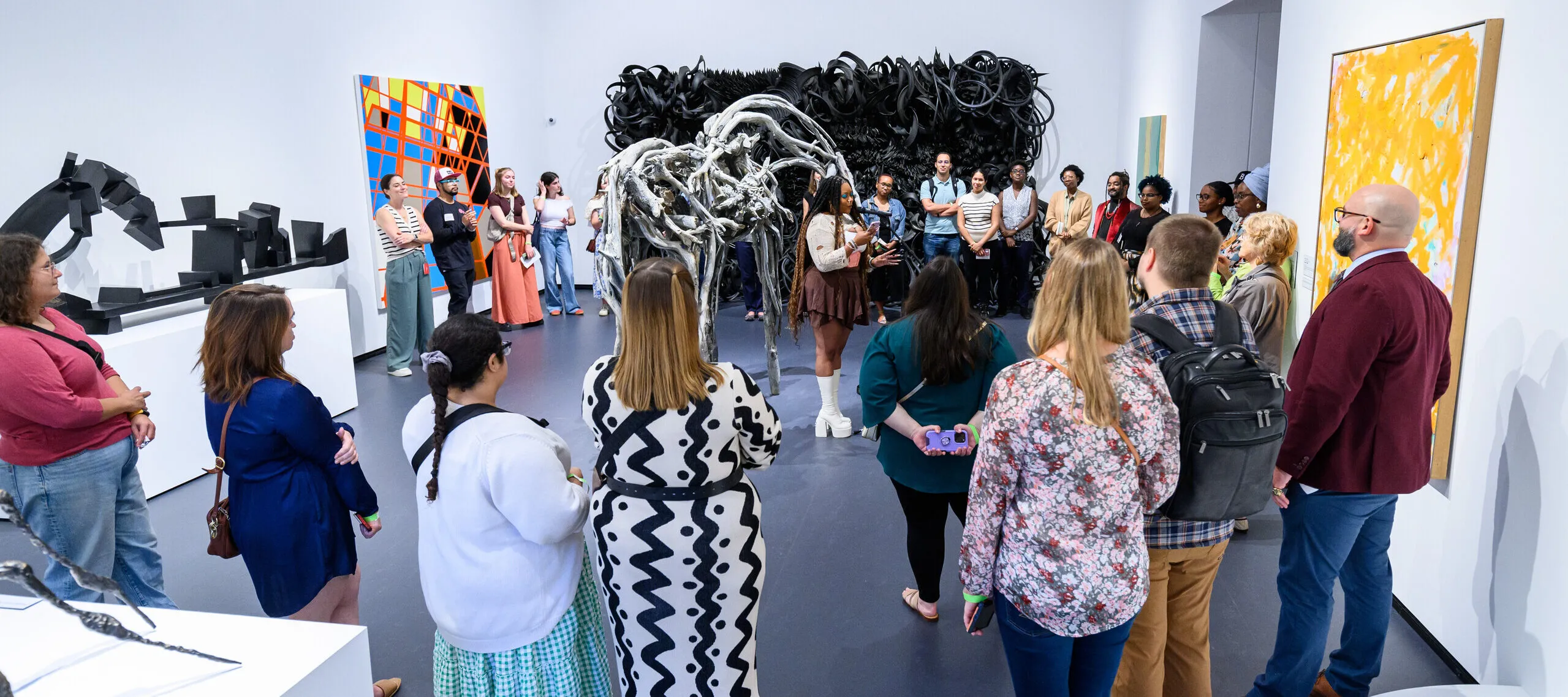 A poet performs in a gallery with many people surrounding her.