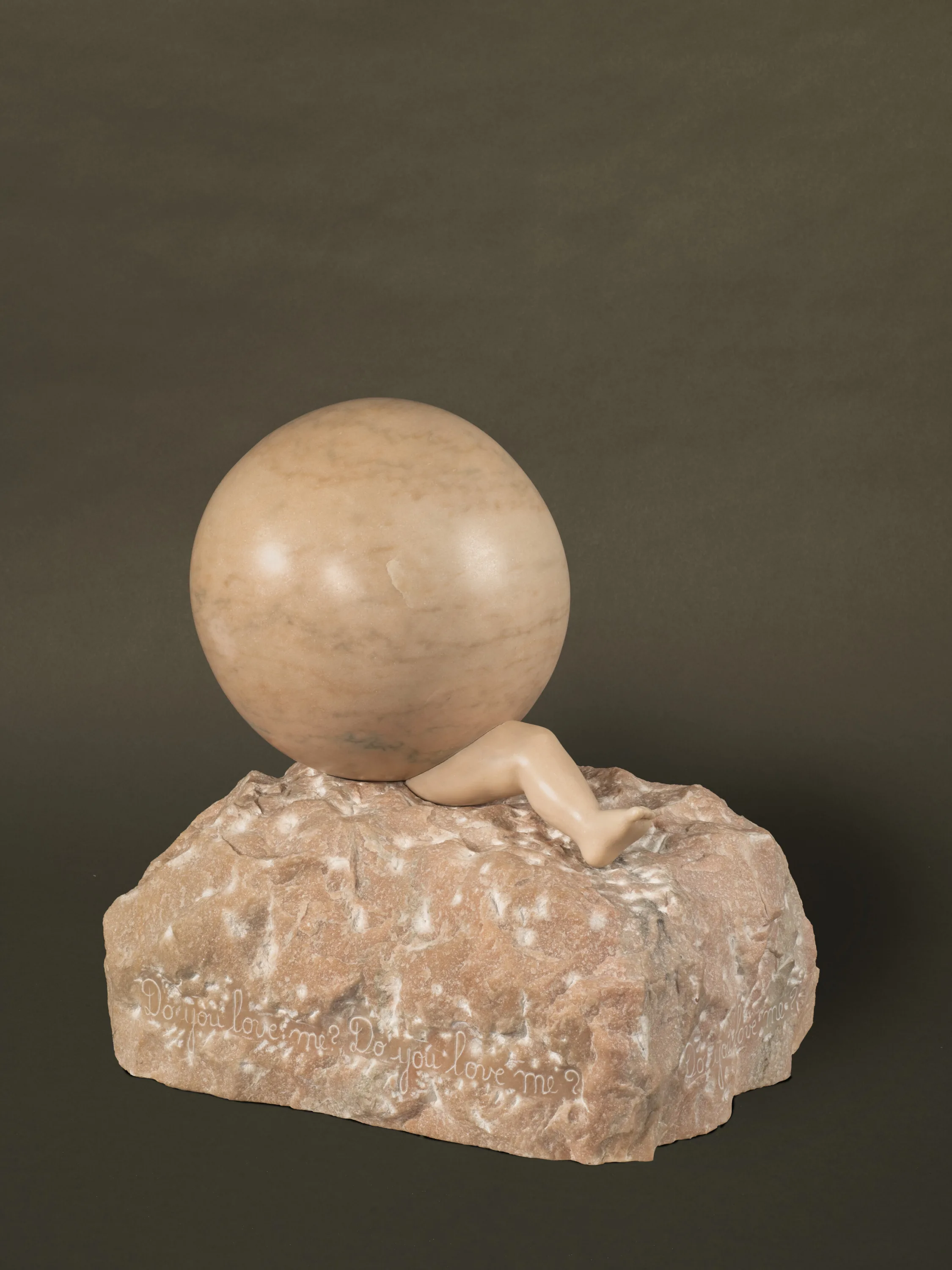 A pink marble sculpture of a smooth round ball, under which protrudes a single leg, as if the person has been crushed by the sphere. Carved into the base is the phrase "Do you love me? Do you love me?" Requires Advance ARS Approval