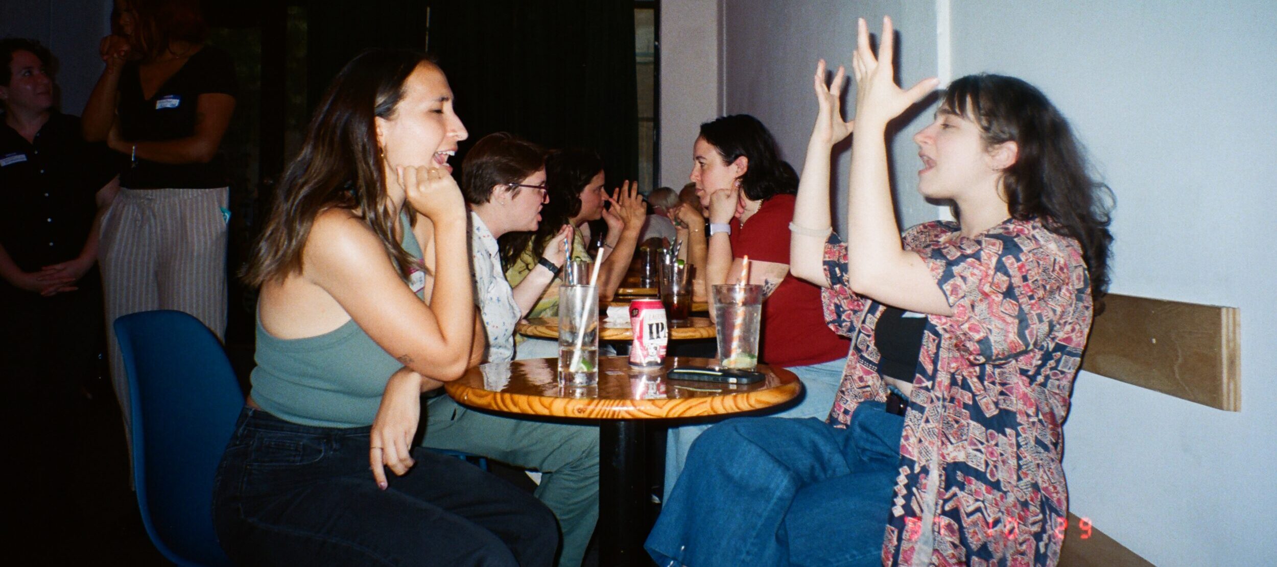 Several groups of young adults sit in a bar having animated conversations.