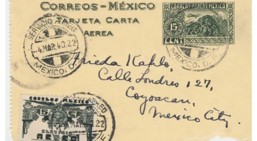 Handwritten envelope on yellowed paper with the image of a palace, stamps, and an address.