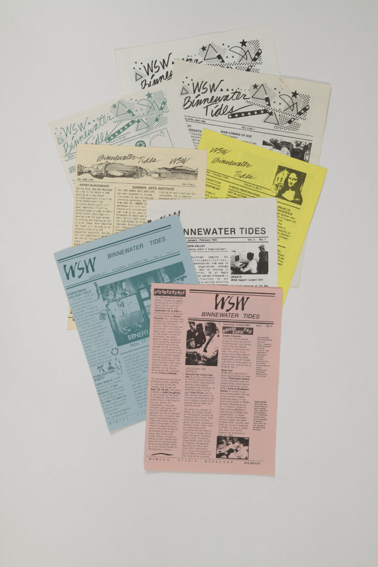 A collection of newsletters printed on light pink, blue, yellow, and white paper is arranged neatly on a white background.