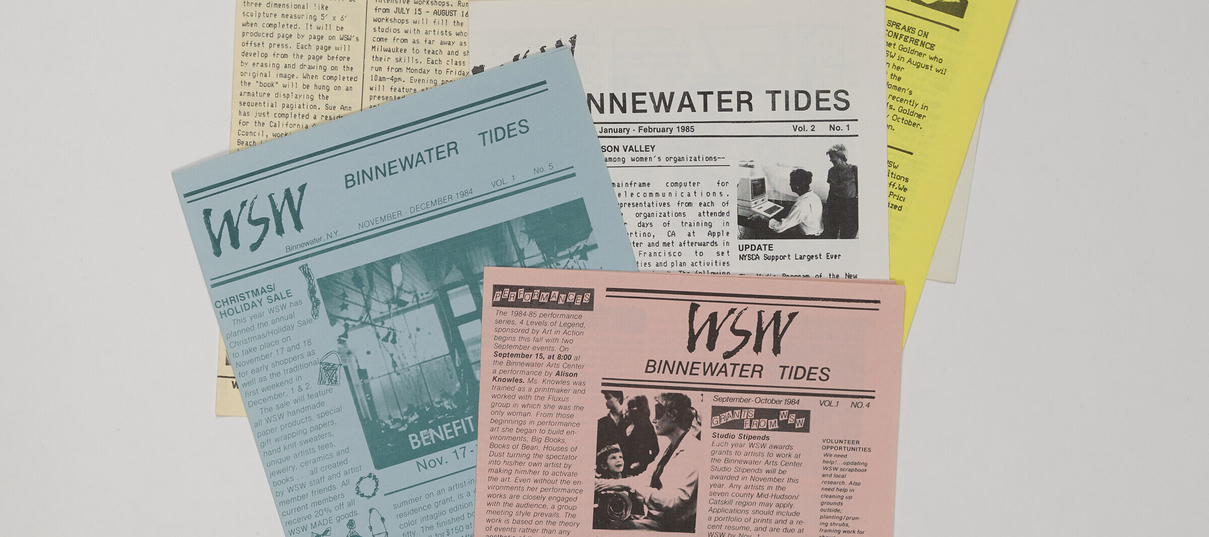 A collection of newsletters printed on light pink, blue, yellow, and white paper is arranged neatly on a white background.