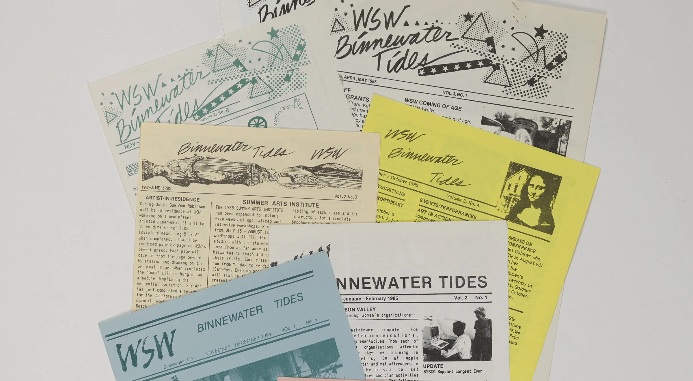 A collection of newsletters printed on light pink, blue, yellow, and white paper is arranged neatly on a white background.