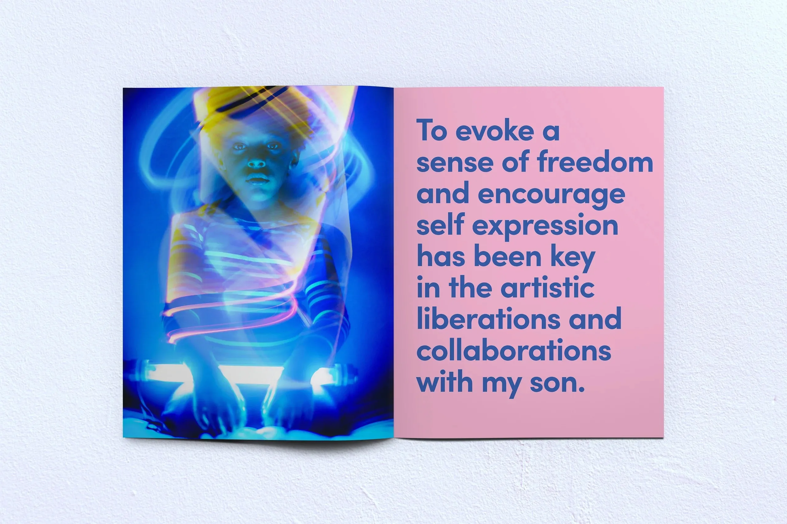A colorful interior spread of a zine features a full-page photograph on the left and a large bold quote on the right. The photo is of a young child lit up and encapsulated by futuristic swirls of blue light emanating from something he holds on his lap.