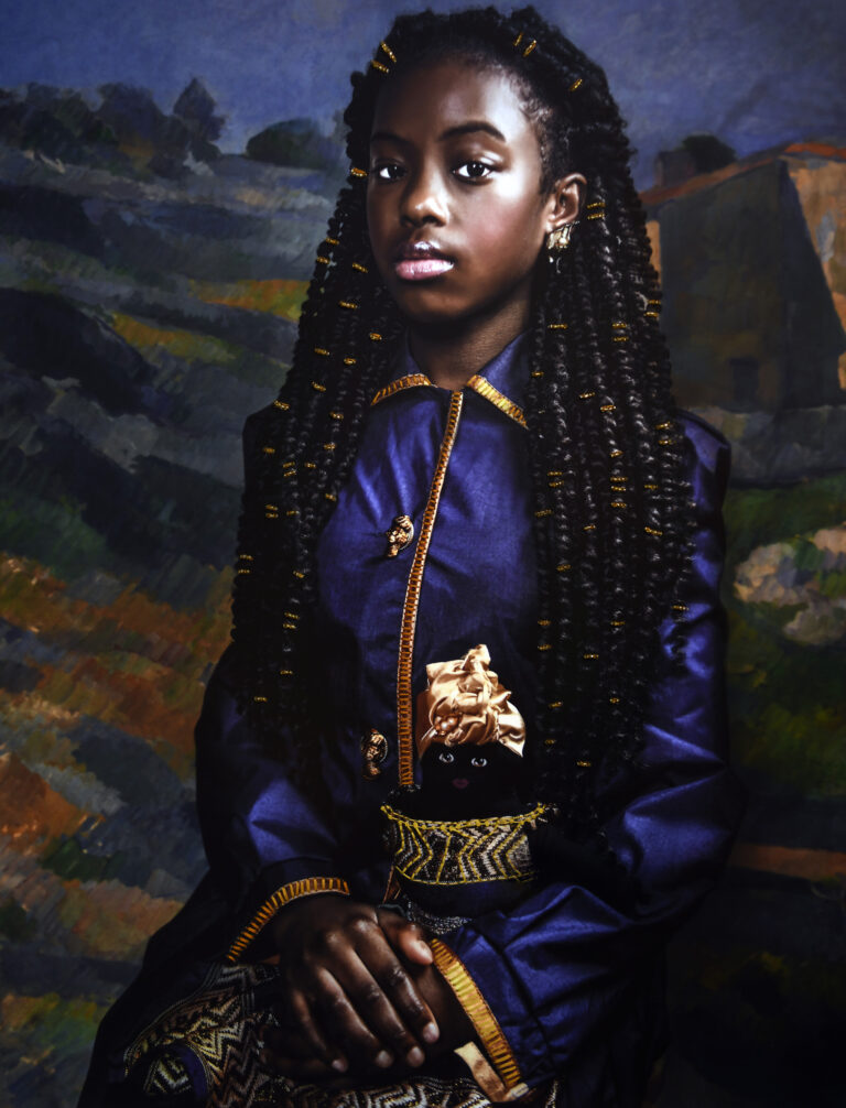 A photograph of a young Black girl. She is seated and wearing a blue dress with gold accents. She holds in her lap a doll, which is dressed in a gold dress and headwrap. The background is a landscape painting by Cezanne.