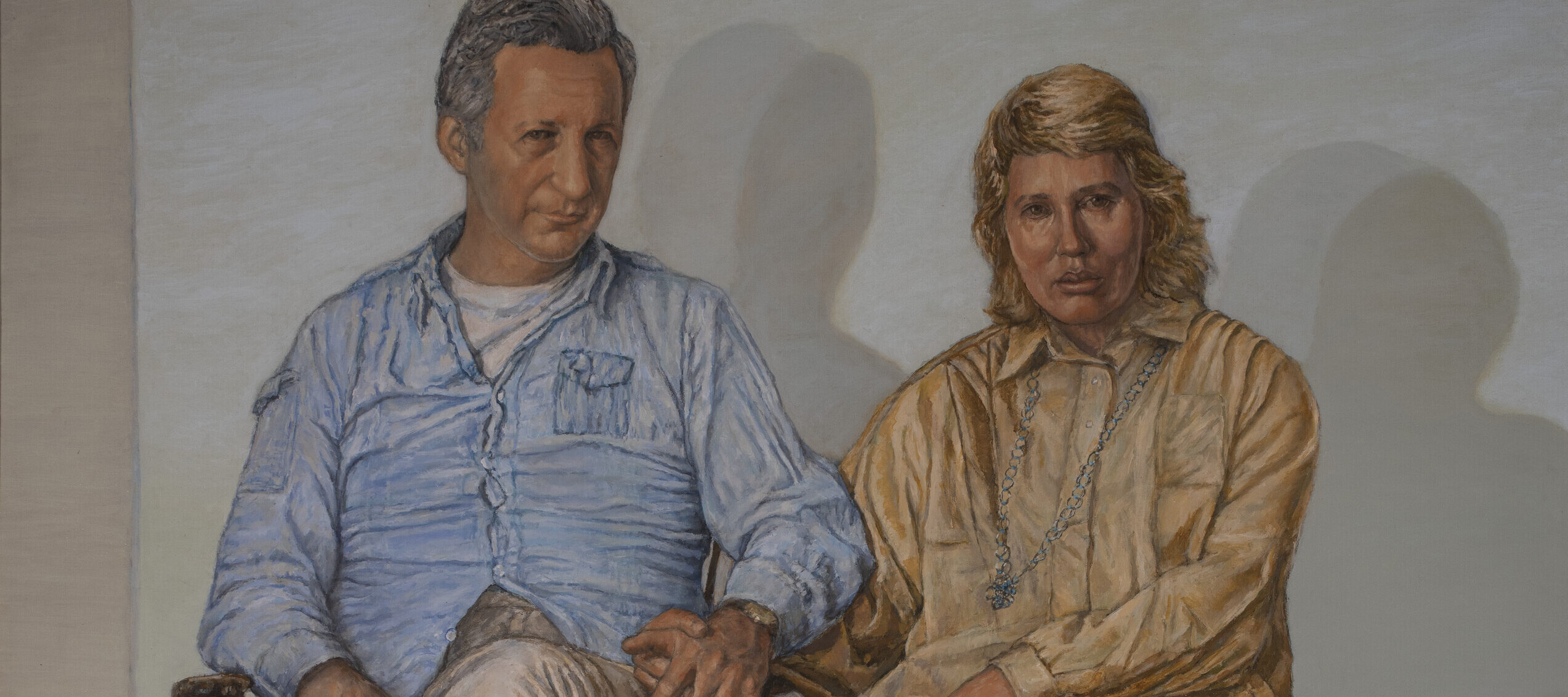 Two depictions of the same woman are shown in a room with an orange-tiled floor. One stands with a hand on her hip, while the other sits on a striped chair draped in green fabric. Both cast shadows on the plain wall behind them.