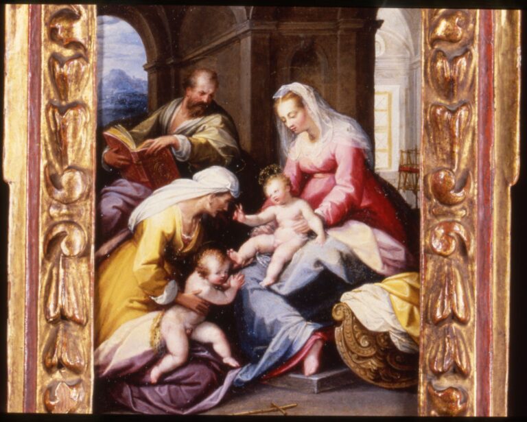 An ornate, gold-and-red wooden frame with intricate carvings surrounds a religious painting of five figures with light skin tone. The painting depicts two women seated holding babies and a man seated above observing downward.