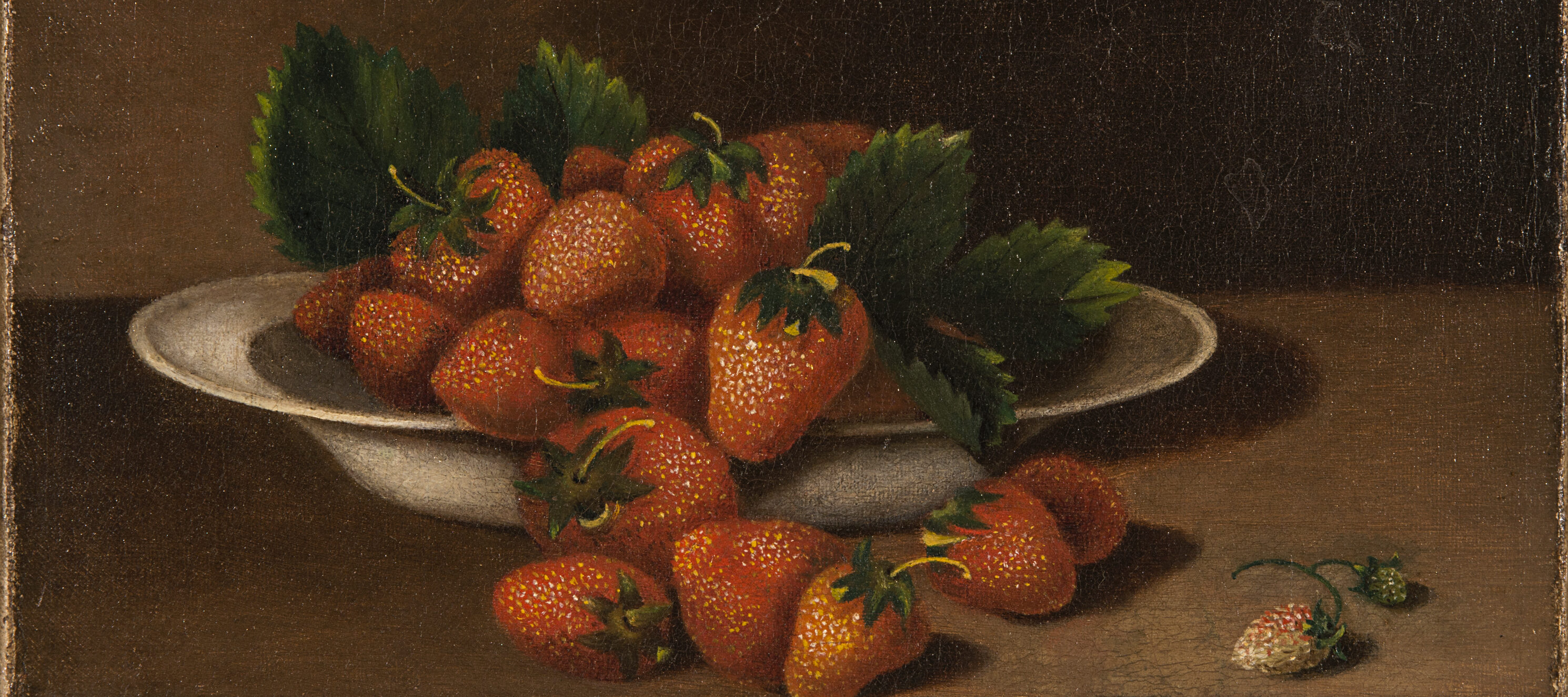 A realistic rendering of a bowl of strawberries with green leaves and yellowing stems overflowing onto the wooden table beneath. To the right, there are two small berries not yet ripe.