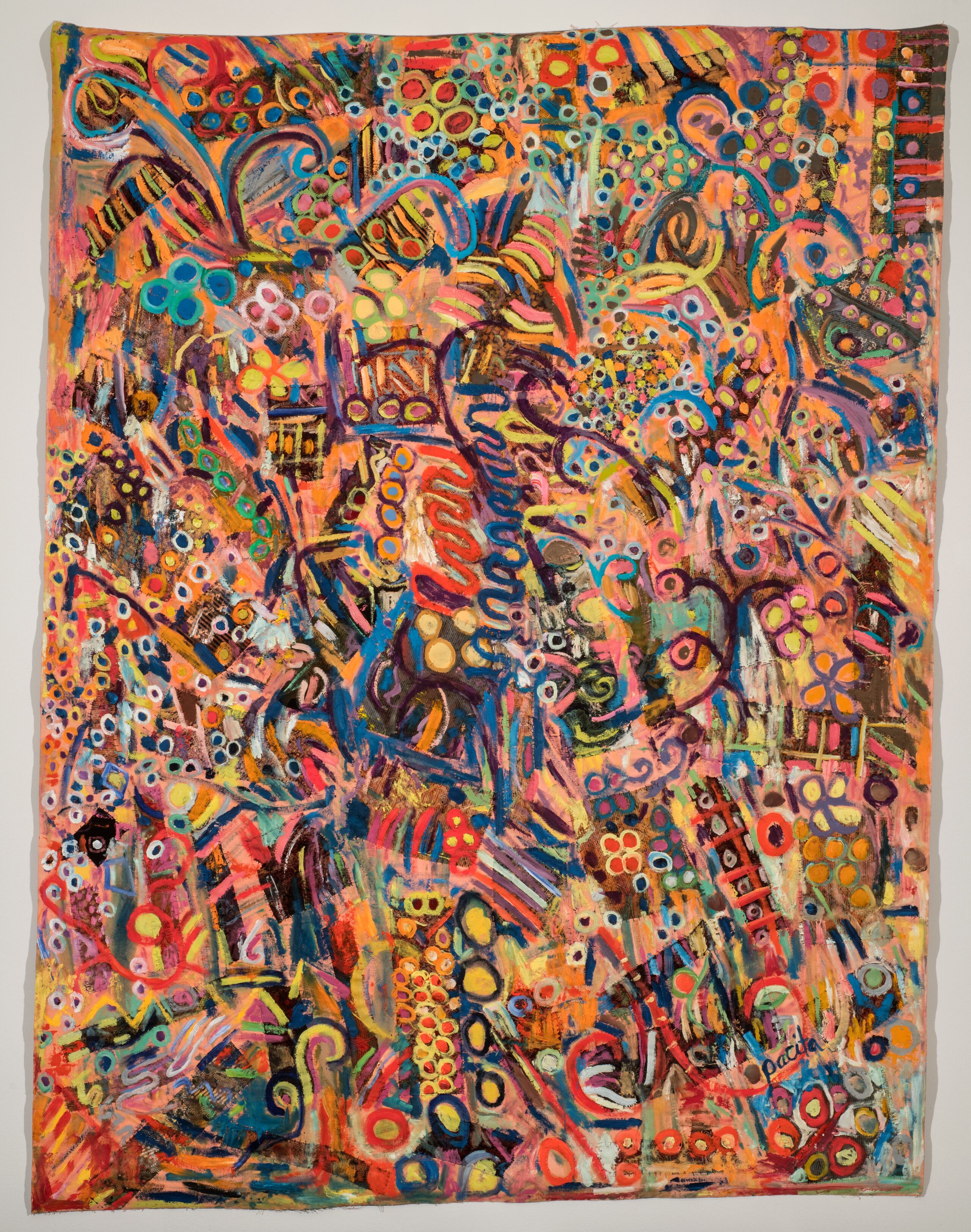 A large, rectangular, abstract artwork combines painting and varied textiles. Its myriad colorful shapes and lines, in rusty orange tones, saturated blues, and many other tones, lend it a sense of energy and movement that is intensified by looping, circling, and squiggling lines of paint.