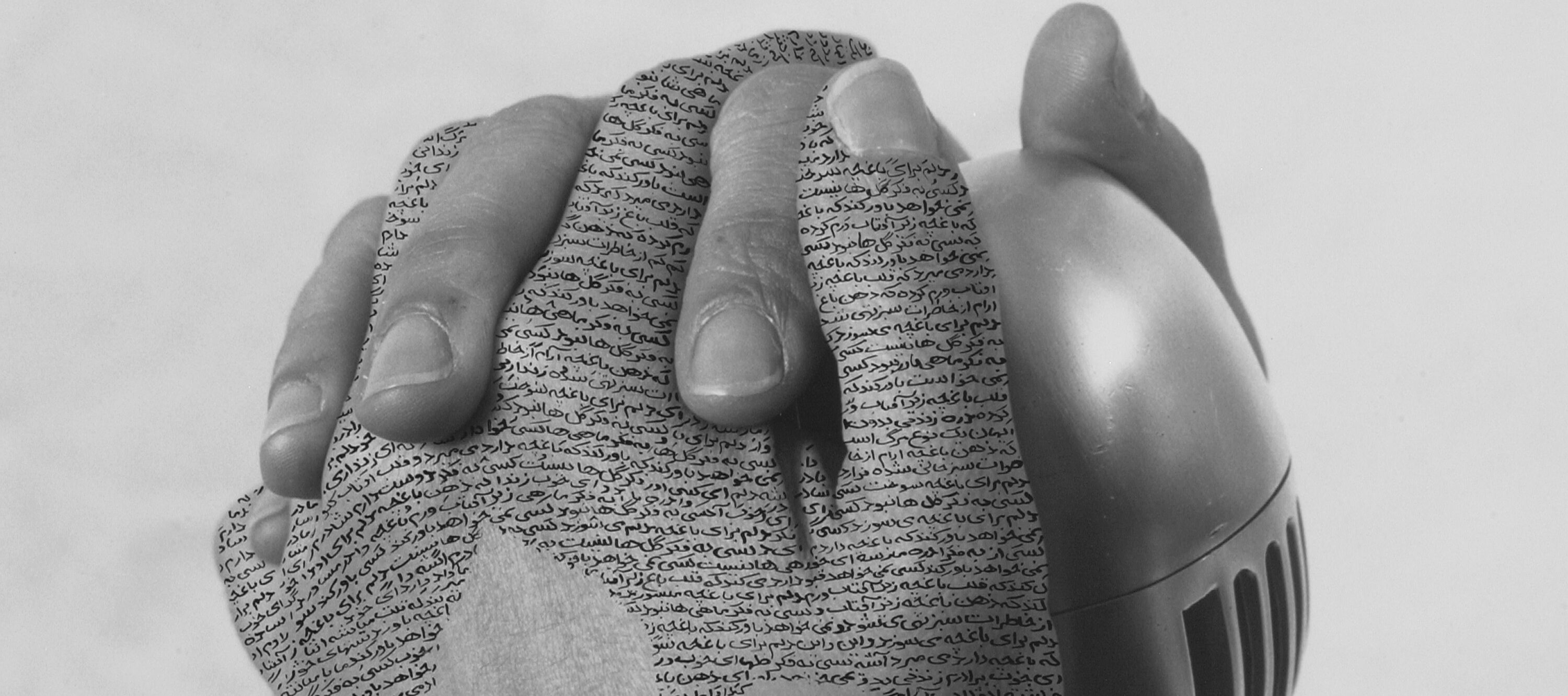 Close-up, black-and-white photograph of a woman's hands with fingers interlaced around a silver, vintage microphone. Lines of poetry inscribed in Farsi form a three-leaf shape on her left hand.