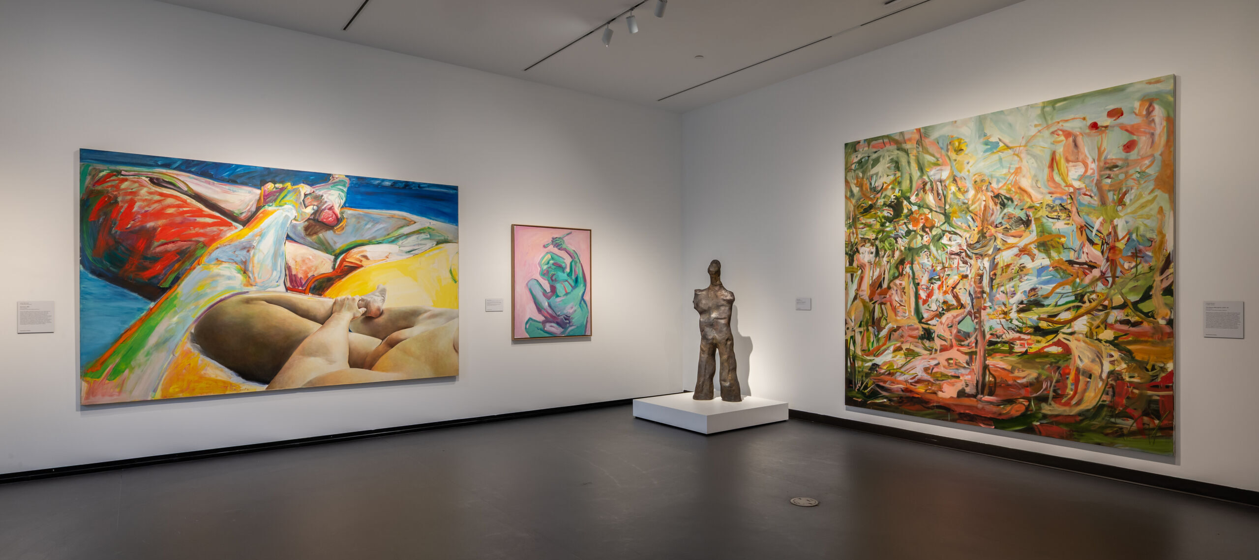 View of an indoor art gallery space with abstract artworks on the walls and sculptures on the floor.
