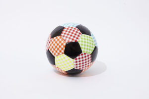 A soccer ball with panels in various colors and checkered patterns, including red, green, blue, orange, and yellow, mixed with traditional black panels, on a white background.