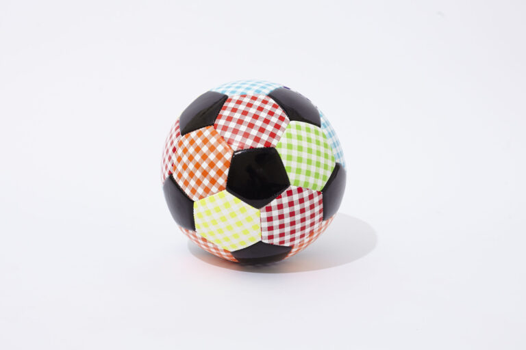 A soccer ball with panels in various colors and checkered patterns, including red, green, blue, orange, and yellow, mixed with traditional black panels, on a white background.
