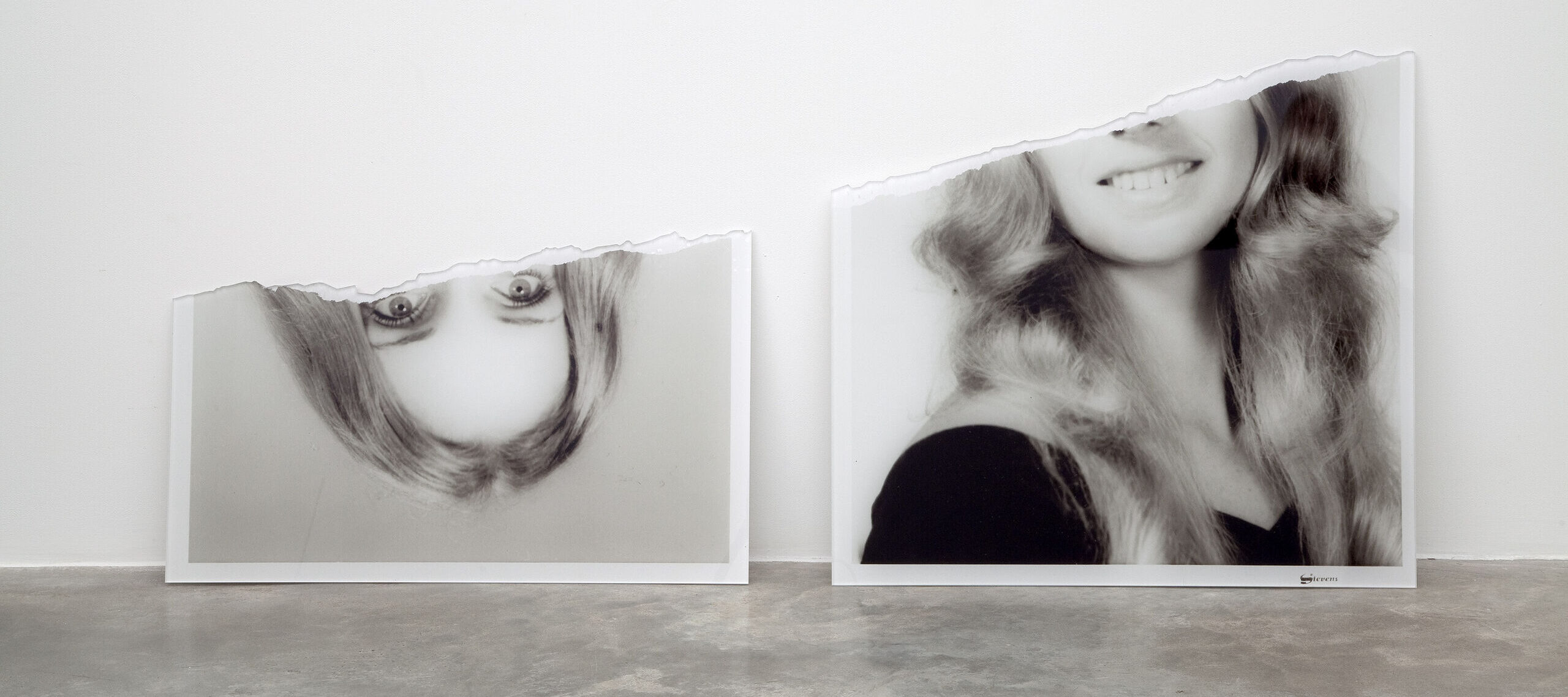 A black and white photograph of a woman with light complexion an blond hair torn in half. The upper half of the photo rests upside down next to the bottom half.