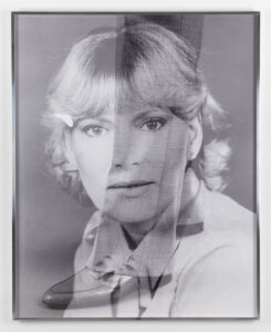 A black and white bust-length image of a woman with light complexion and blond hair over which is superimposed a pair of legs wearing plaid pants and shiny leather shoes.