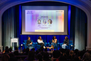 Four women sit on stage discussing in front of an audience, with a projected screen behind them showing event details for the Well-Read Black Girl Festival 2025 at the National Museum of Women in the Arts.