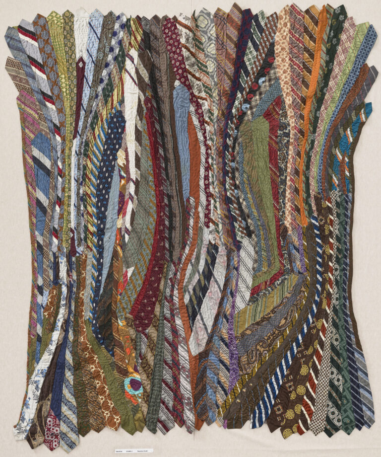 A quilt made of undulating neckties in a variety of colors.