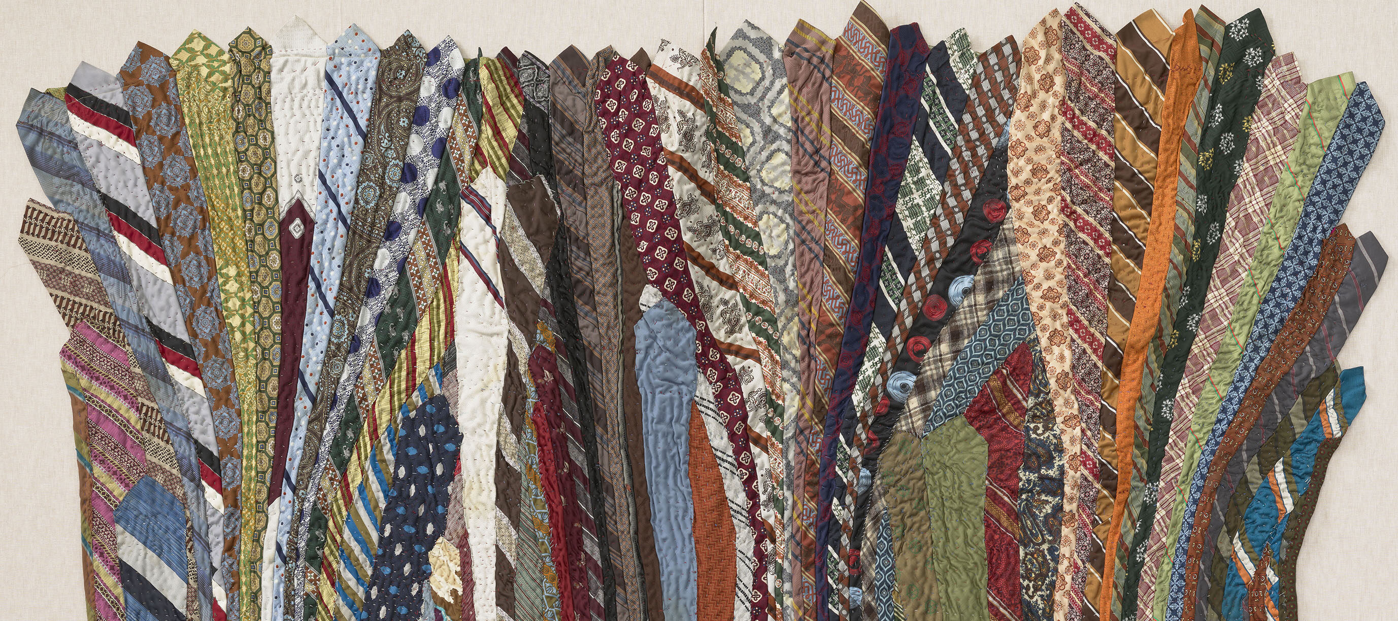 A quilt made of undulating neckties in a variety of colors.