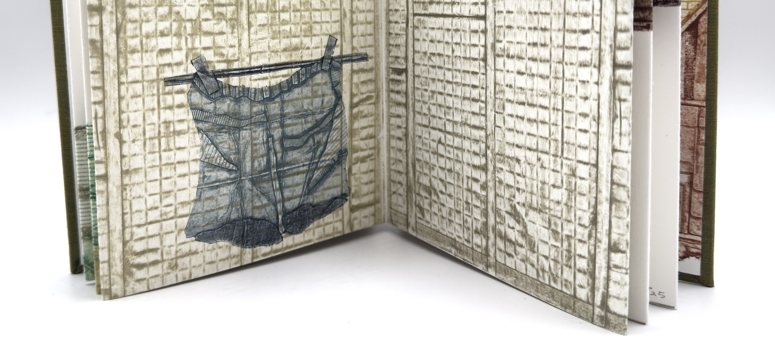 An open book with an image spread across both facing pages. The background of the page image has a grid in light brown; on the page to the left is a drawing of a pair of shorts on a line in blue.