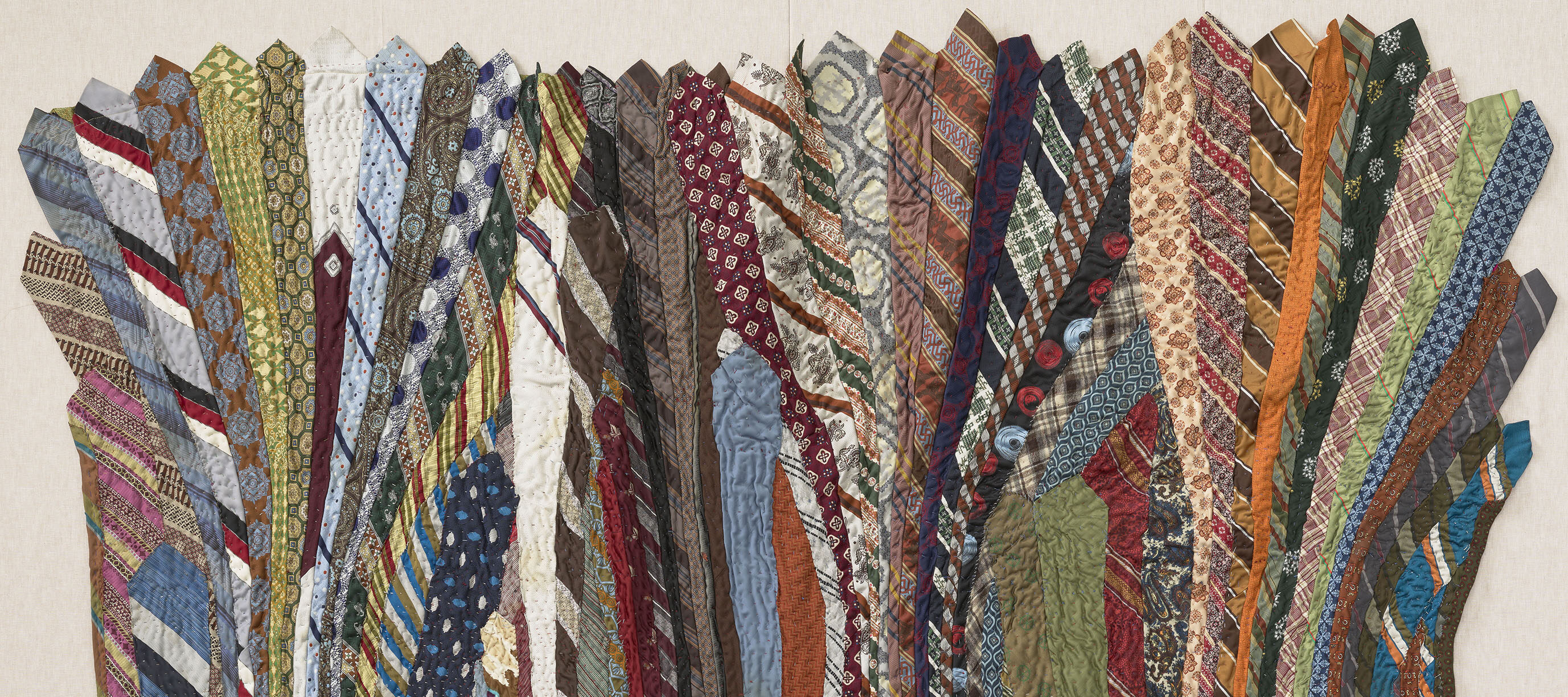 A quilt made of undulating neckties in a variety of colors.
